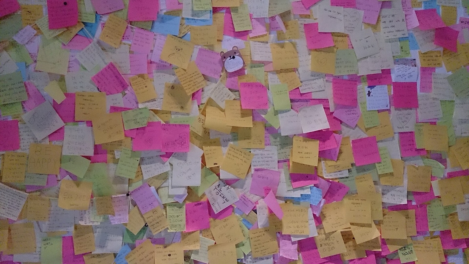 A wall covered edge to edge in yellow, pink, green and white paper notes.
